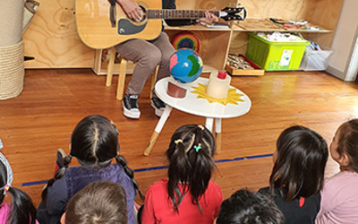 Teacher and children singing peace at Little Earth Montessori Remuera childcare